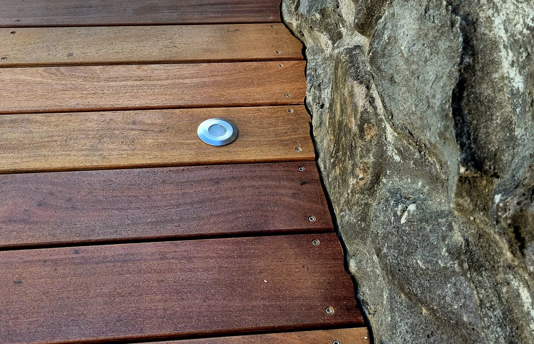 Terrasse en bois exotique découpée au millimètre pour épouser un mur de basalte, réalisée par AMMO à La Réunion
